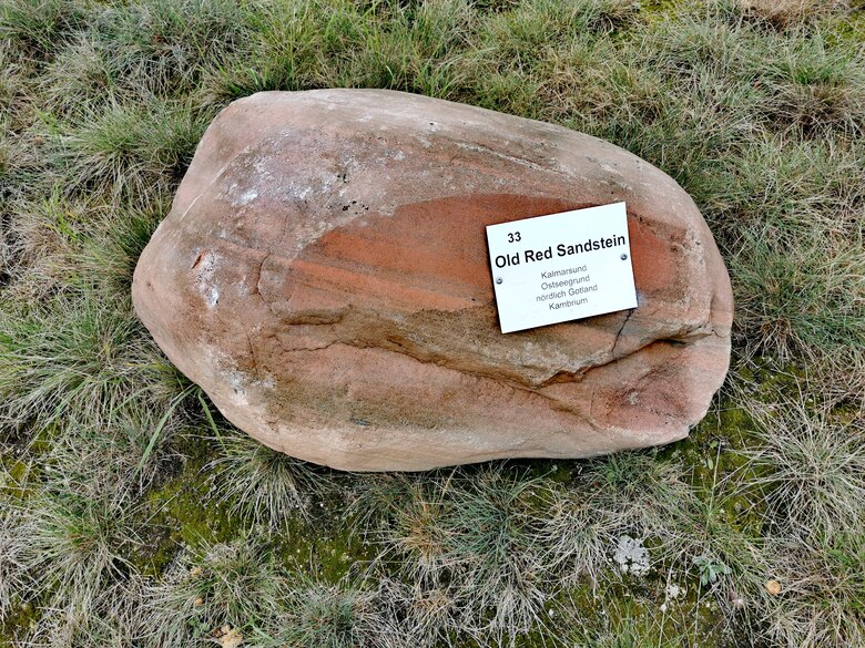 Findling aus rotem Sandstein mit Metallschild, welches seine Herkunft aus dem Kalmarsund nennt.
