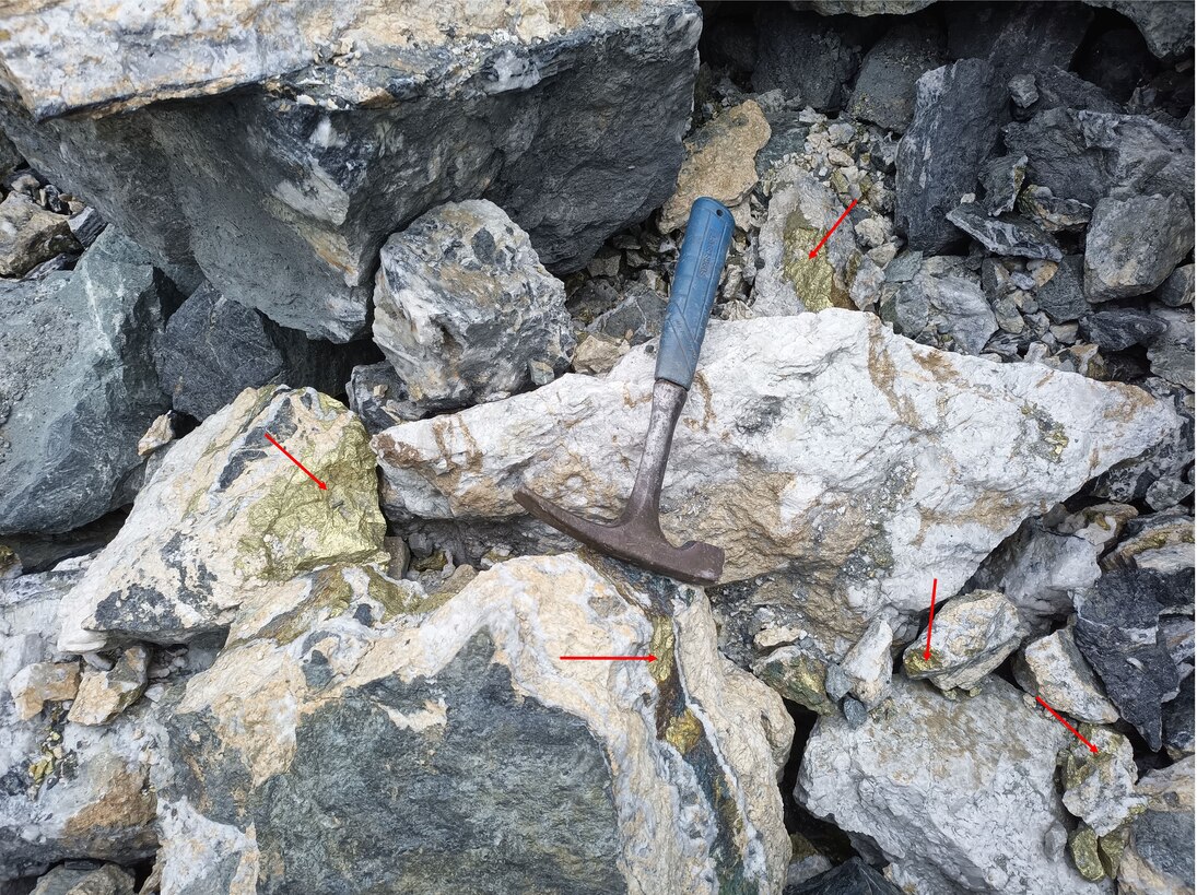 Goldfarbener Chalkopyrit (mit roten Pfeilen gekennzeichnet) liegt derzeit verstreut im Steinbruch-Haufwerk.