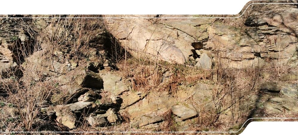 Das Bild zeigt die Steinbruchwand mit geschichtetem Quarzit und Schiefer, die zu einer liegenden Falte deformiert wurden