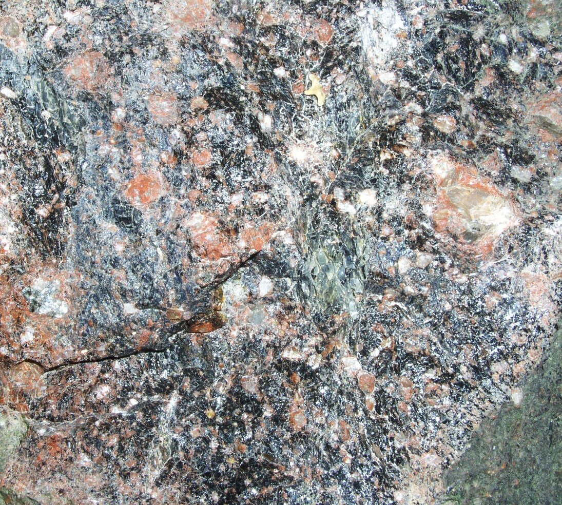 Kugelpechstein, ein Gestein mit schwarzer feiner Grundmasse und roten Zentimeter-großen Kugeln.