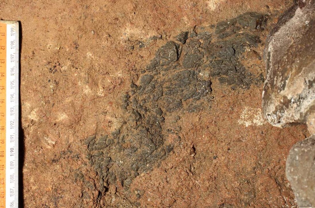 Rötlichbrauner Tuff mit dunklem Basaltschlackeneinschluss aus dem Rest eines Basaltschlackenwalls in Stolpen.