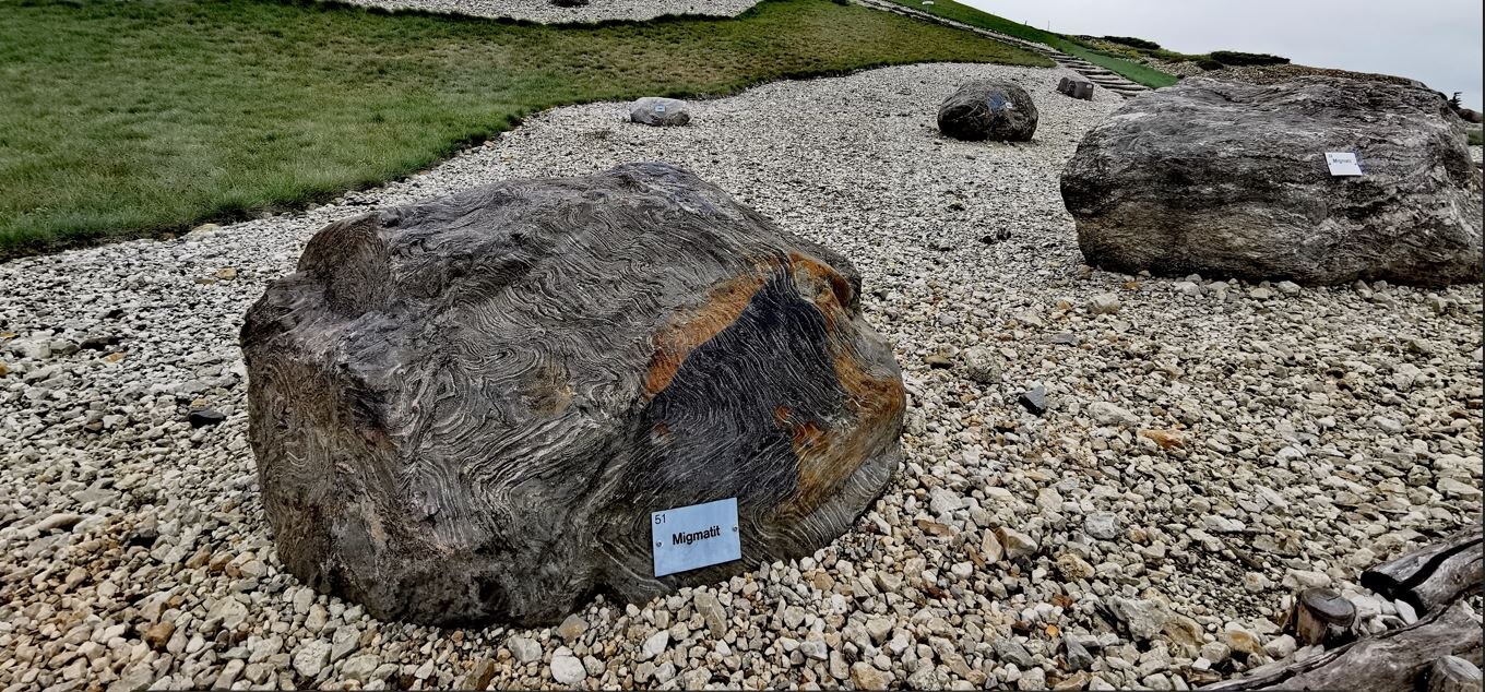 Kiesgarten, in dem mehrere Findlinge mit Schildern liegen.